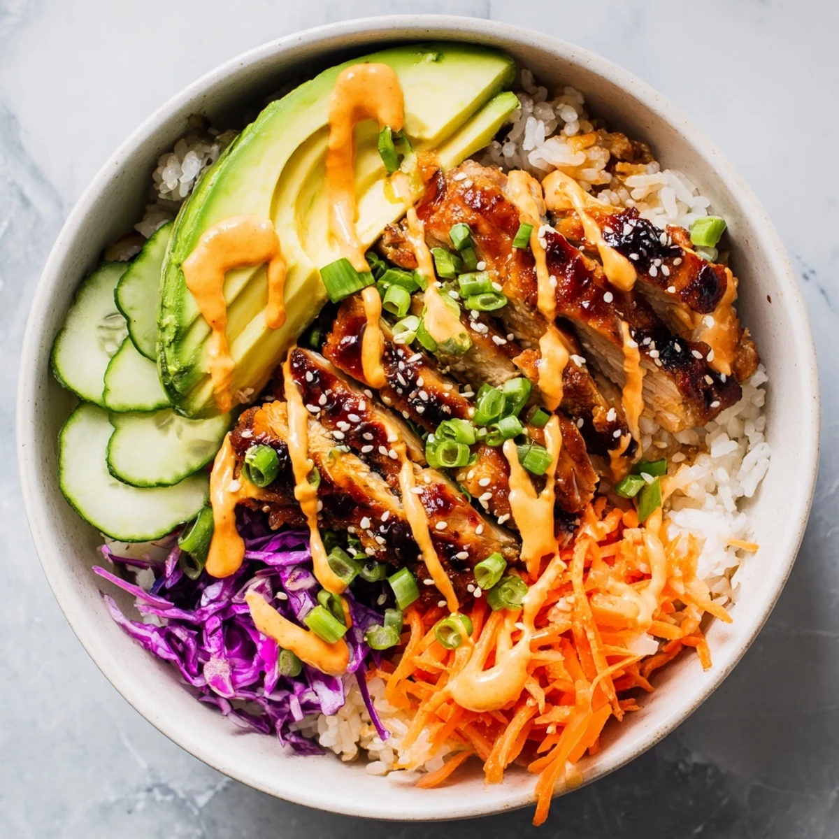 Savory Korean BBQ chicken bowl with juicy marinated meat sliced over rice garnished with purple cabbage avocado and tangy sauce