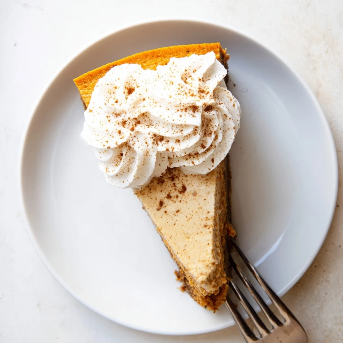 Creamy pumpkin spice Christmas cheesecake slice with whipped cream topping on graham cracker crust