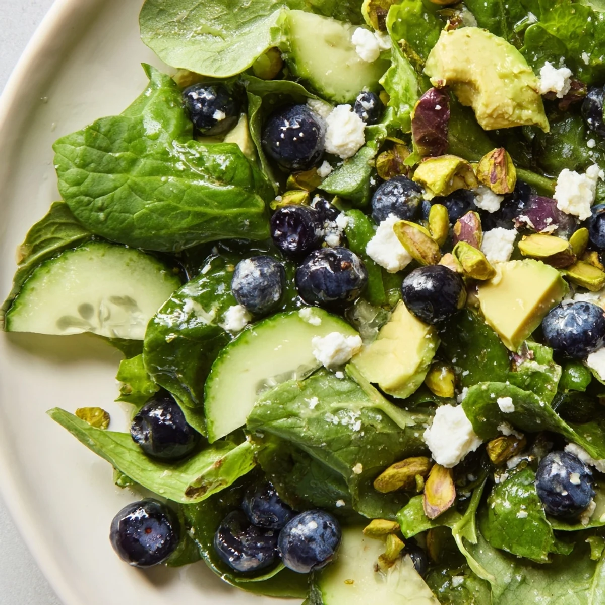 Vibrant Blueberry Pistachio Spring Salad drizzled with tangy lemon honey dressing in wooden bowl