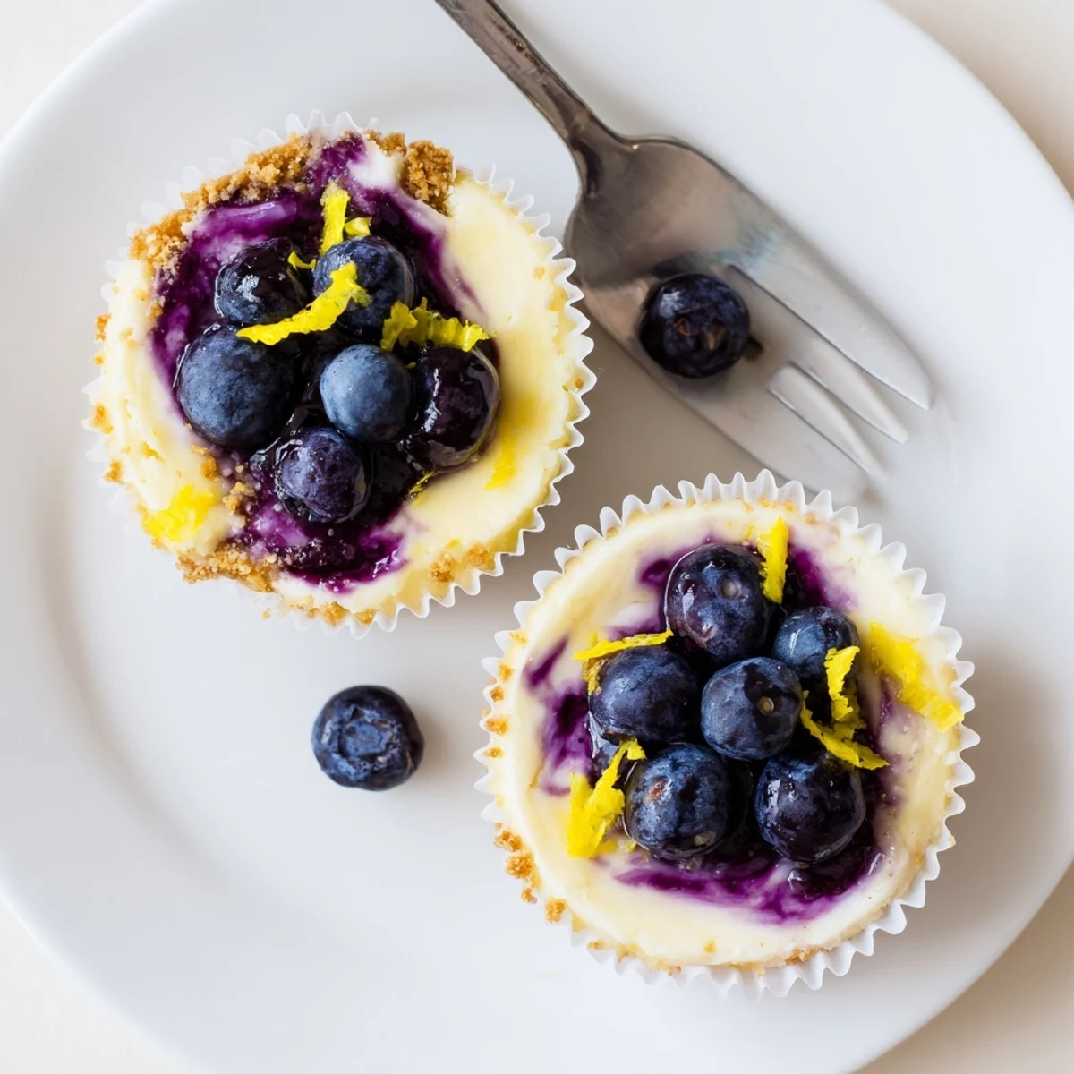 Creamy mini lemon blueberry cheesecakes served chilled on a rustic white dessert plate