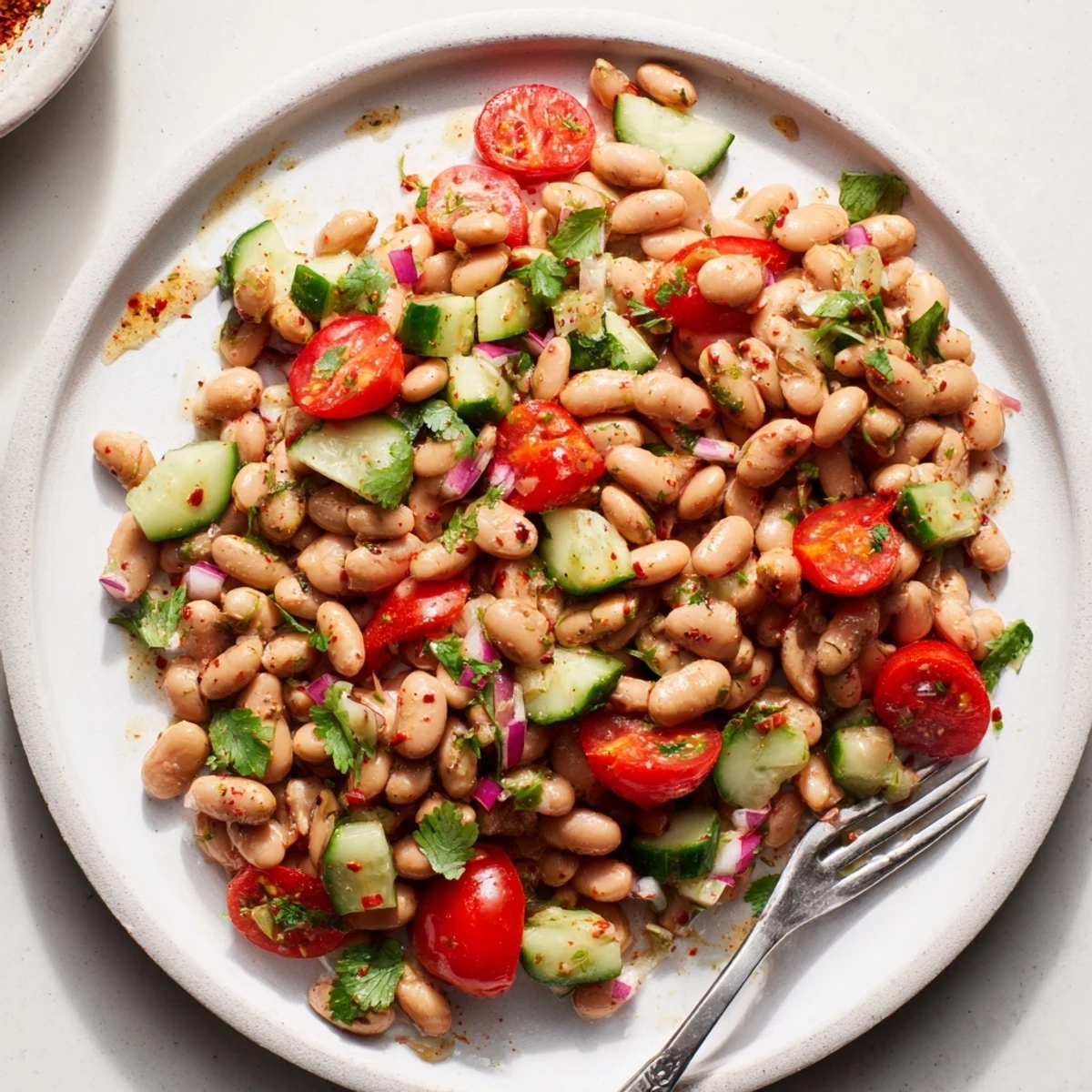 Creamy pinto bean salad garnished with red bell pepper and drizzled with cumin lime vinaigrette