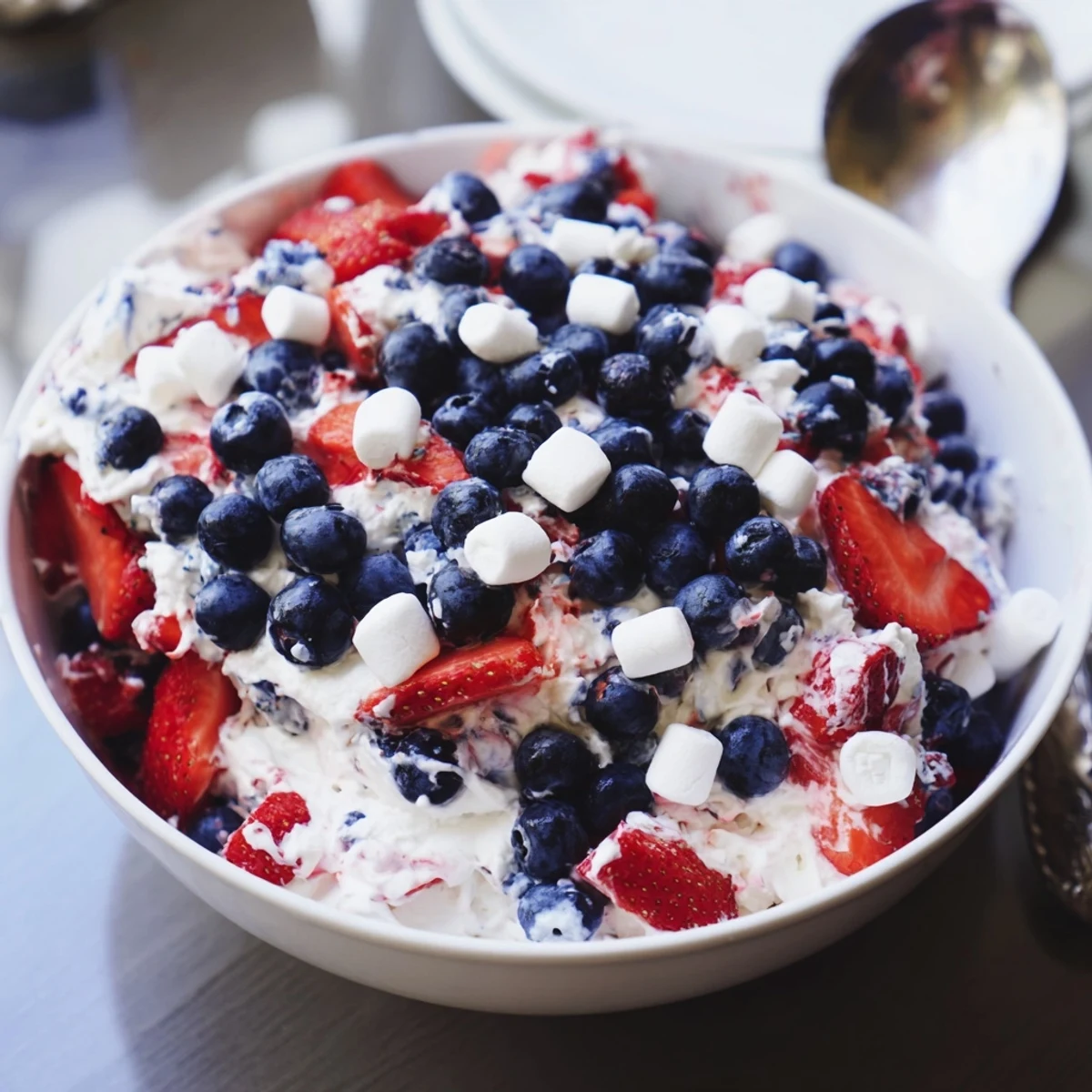 Vibrant strawberries and blueberries nestled in fluffy red white blue cheesecake salad with mini marshmallows