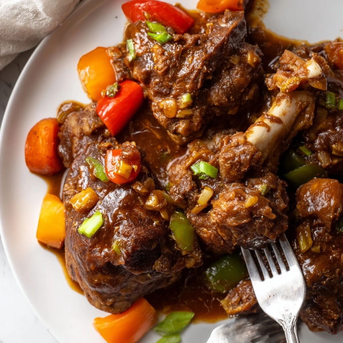 A Dutch oven of Jamaican brown stew chicken with caramelized chicken pieces nestled in thick tomato-based island gravy.