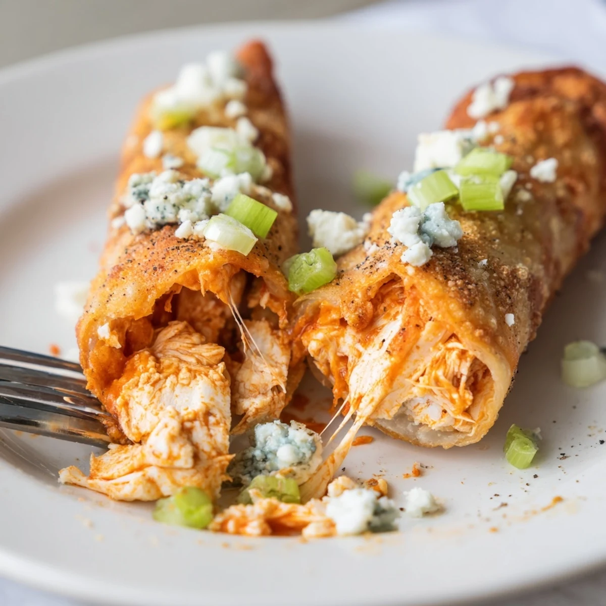 Hot Buffalo Chicken Egg Rolls resting on paper towels, celery and blue cheese