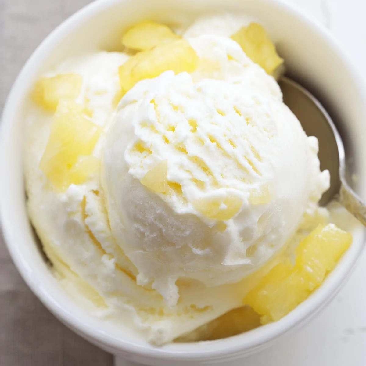 Creamy Pineapple Ice Cream scoops in a chilled bowl, tropical aroma.