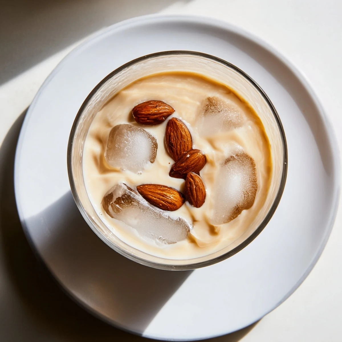 Golden roasted almond milk drink blended with heavy cream and ice cubes on wooden table