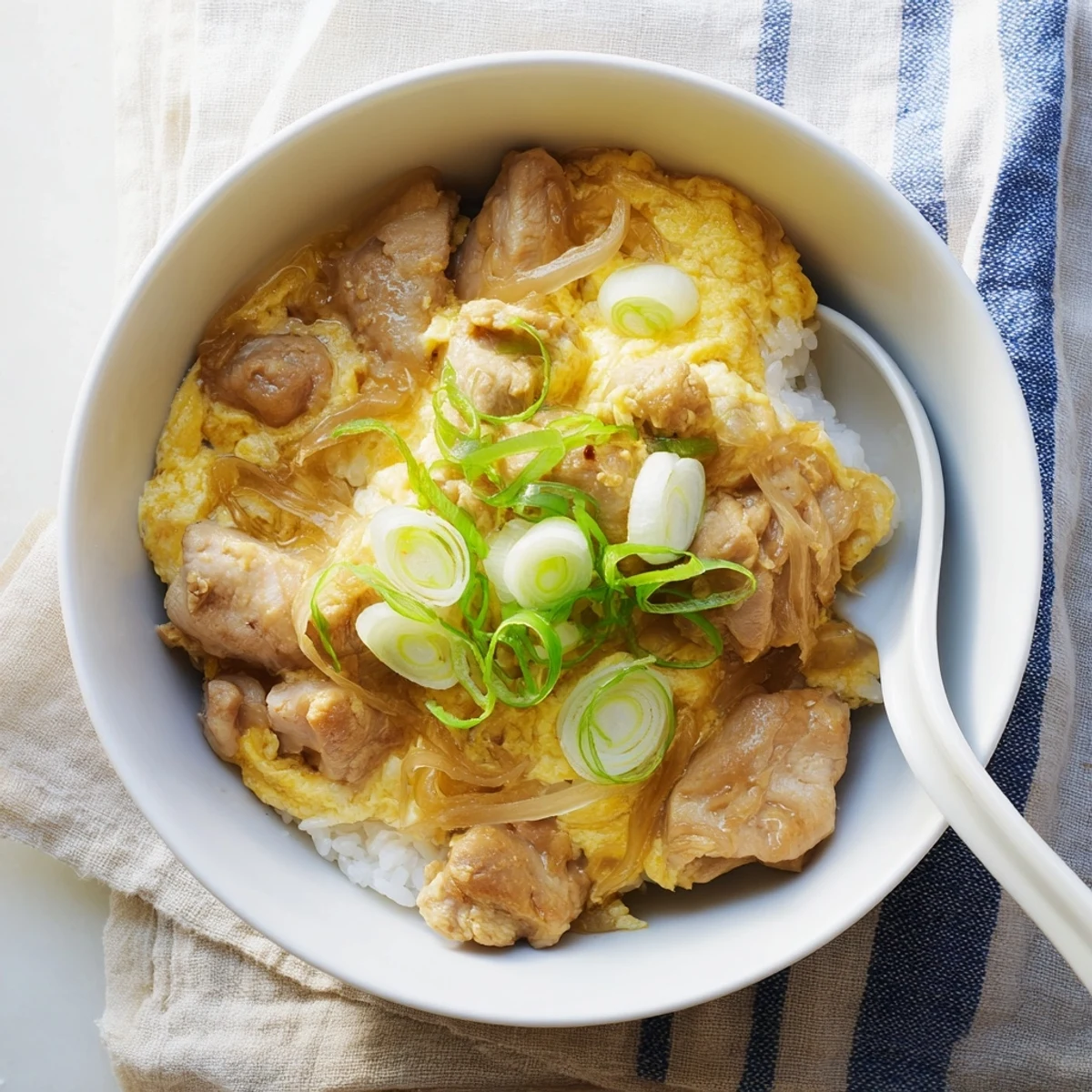 Steaming bowl of one pot Oyakodon featuring tender chicken and softly set eggs over fluffy white rice