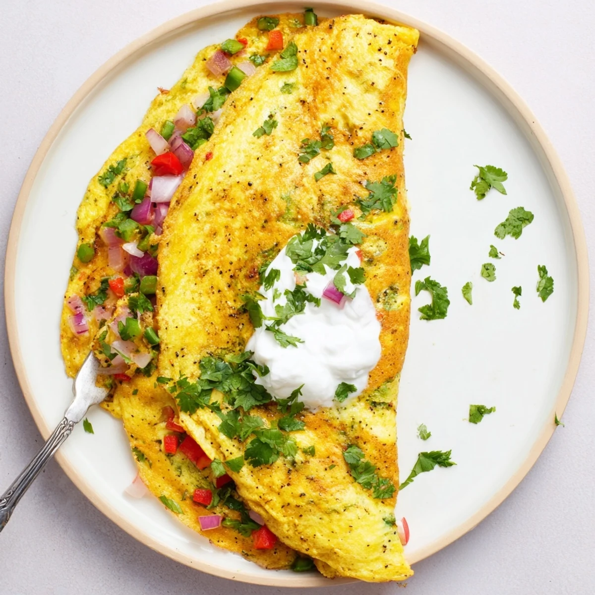 Vibrant vegetarian omelette spiced with turmeric and cumin, garnished with Greek yogurt