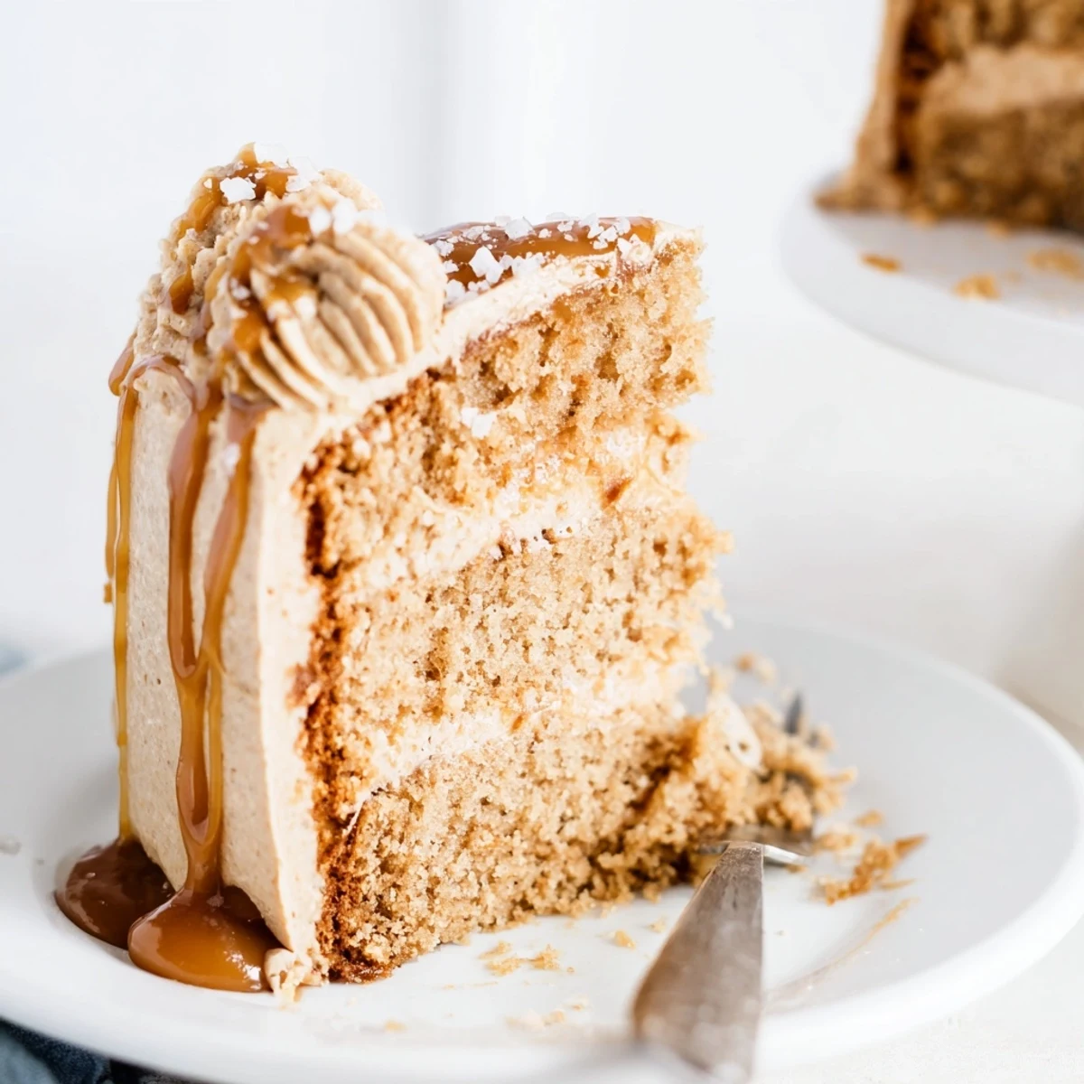 Decadent layered banana cake featuring brown butter, whipped caramel frosting, and golden caramel drizzle