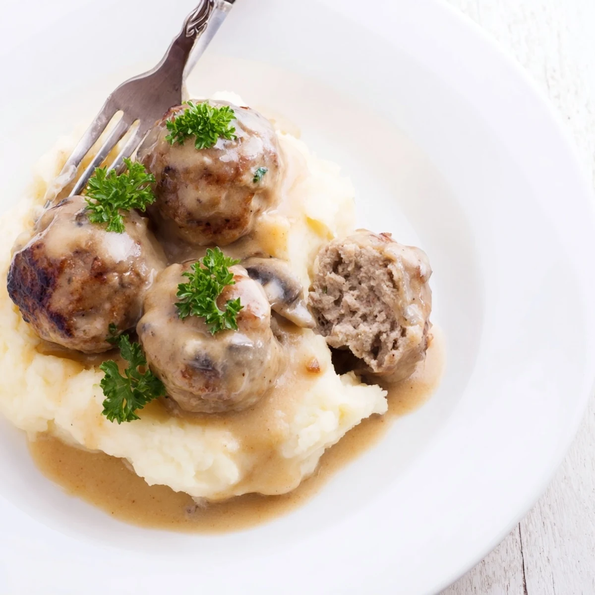 Slow-simmered Crockpot Meatballs Gravy, thick brown sauce spooned over egg noodles.