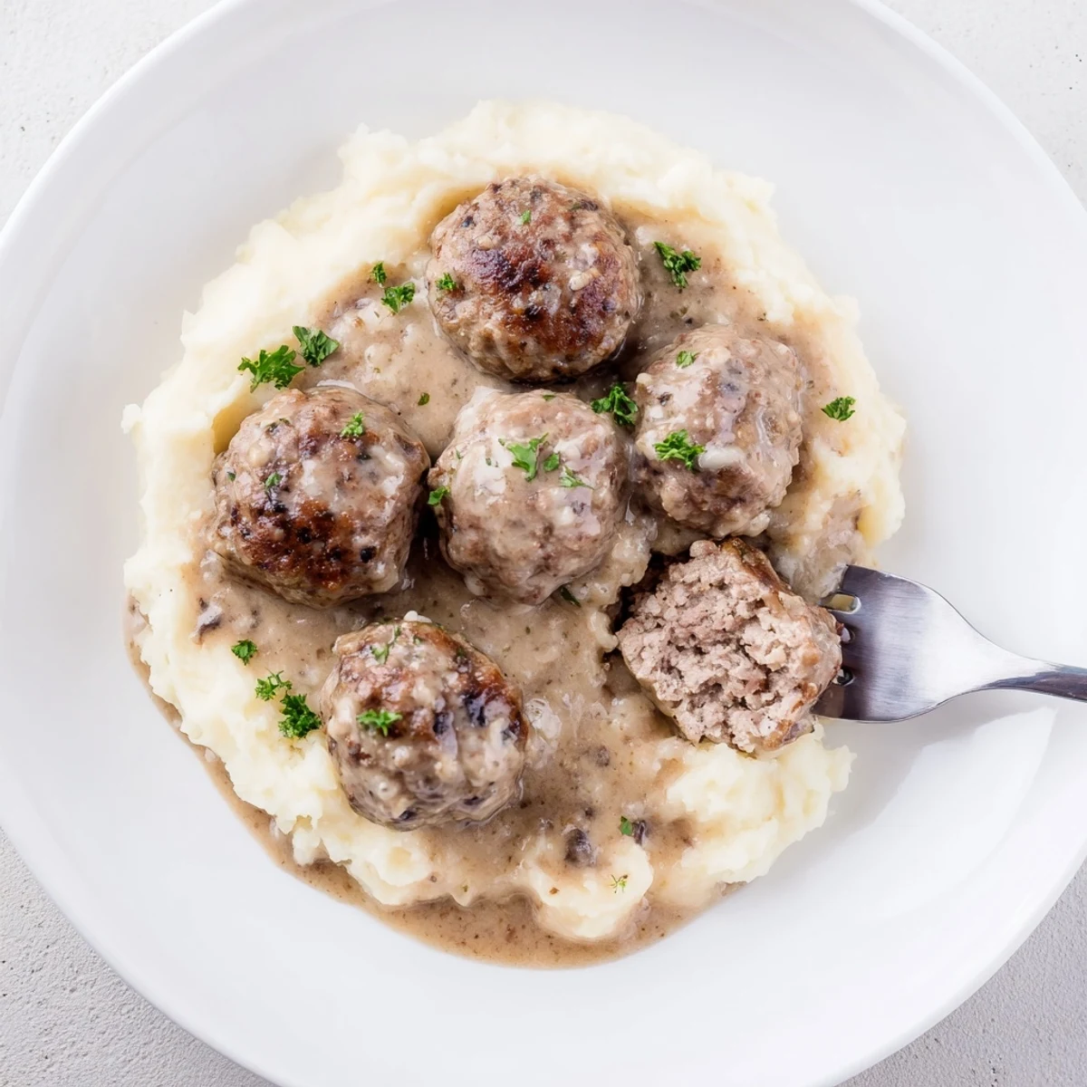 Crockpot Meatballs Gravy bubbling, tender bites nestled over creamy mashed potatoes.