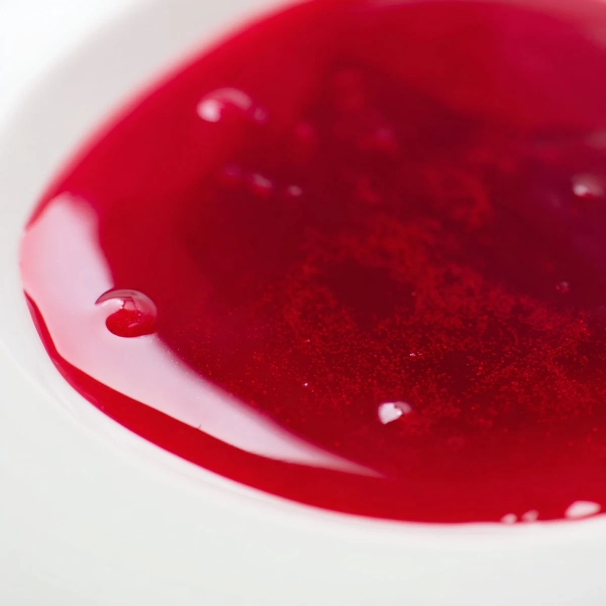 Tangy cranberry syrup poured over vanilla ice cream with sugared cranberry garnish on top