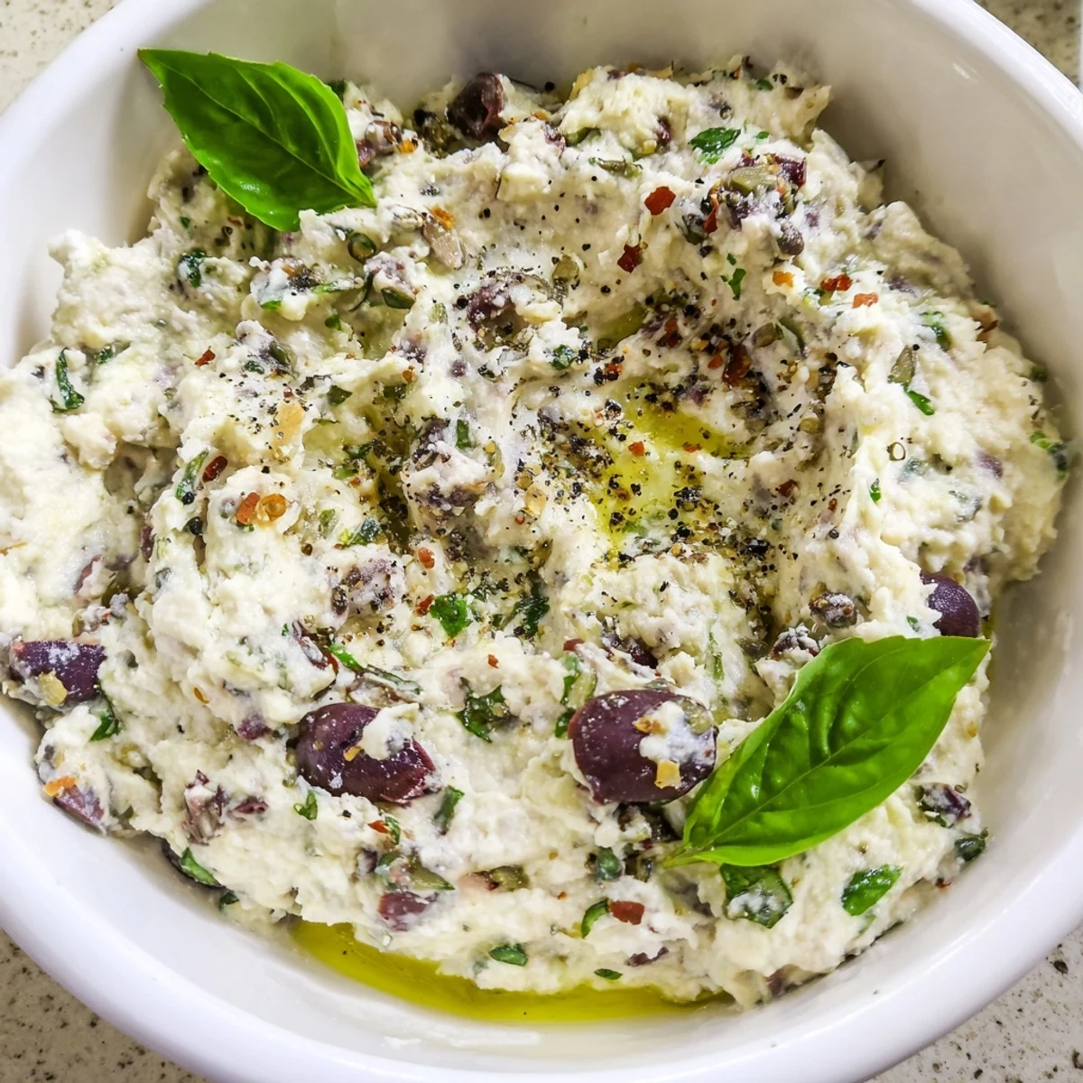 A rustic bowl of Italian Style Olive and Cheese Spread served alongside toasted baguette slices
