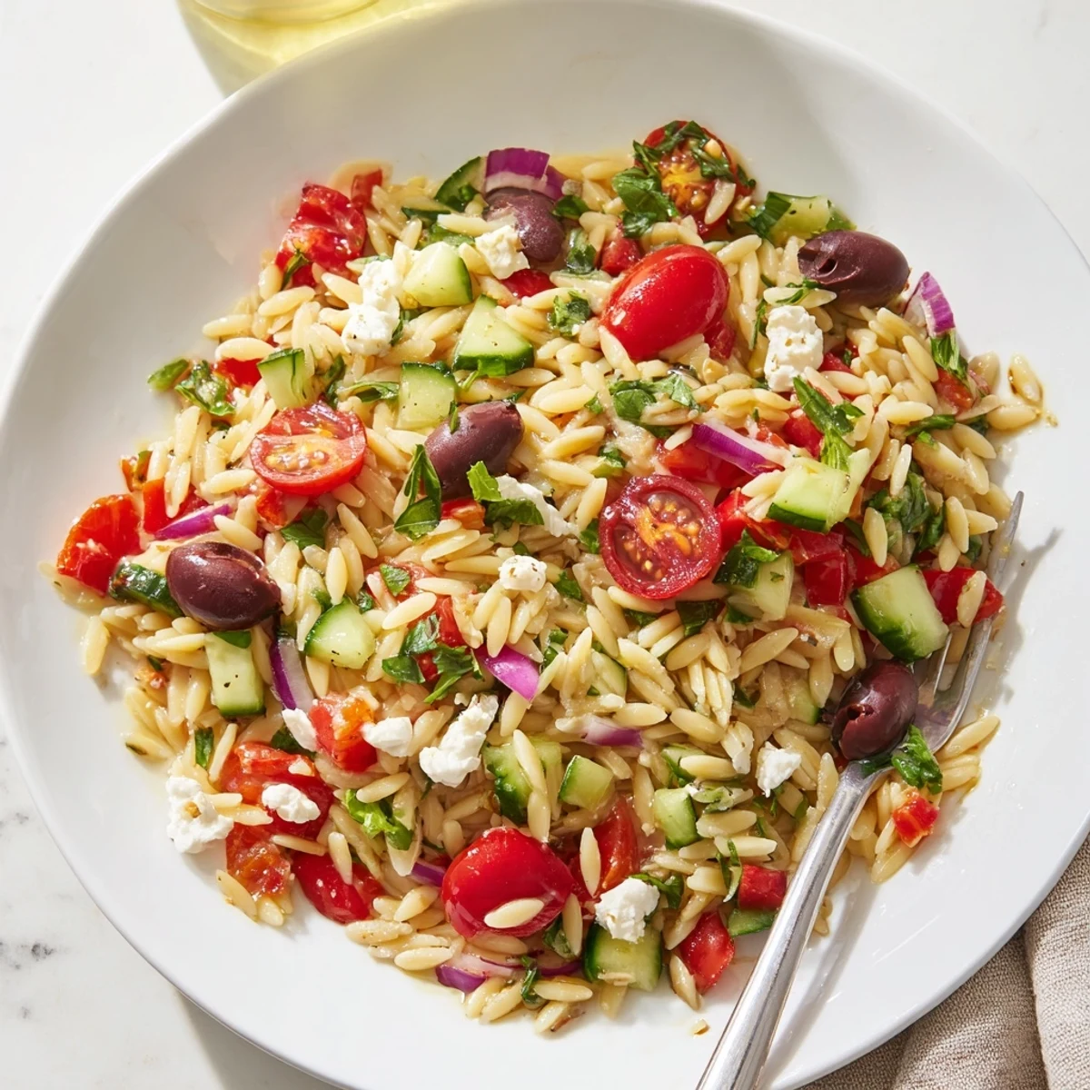 Colorful Mediterranean orzo pasta salad in a bowl with cherry tomatoes and feta