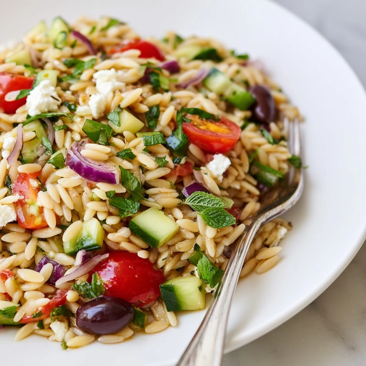 Bright Mediterranean orzo pasta salad served chilled on a sunny picnic table