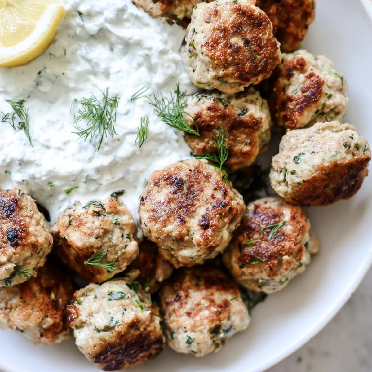 Crispy Greek turkey meatballs with tzatziki served alongside fresh lemon wedges and parsley