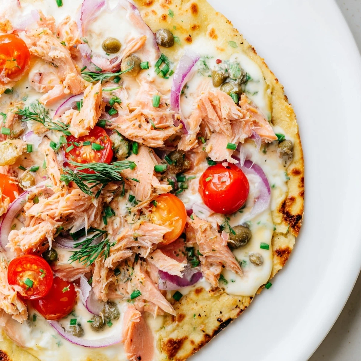 Crispy salmon tortilla pizza with melted mozzarella, capers, and fresh dill garnish