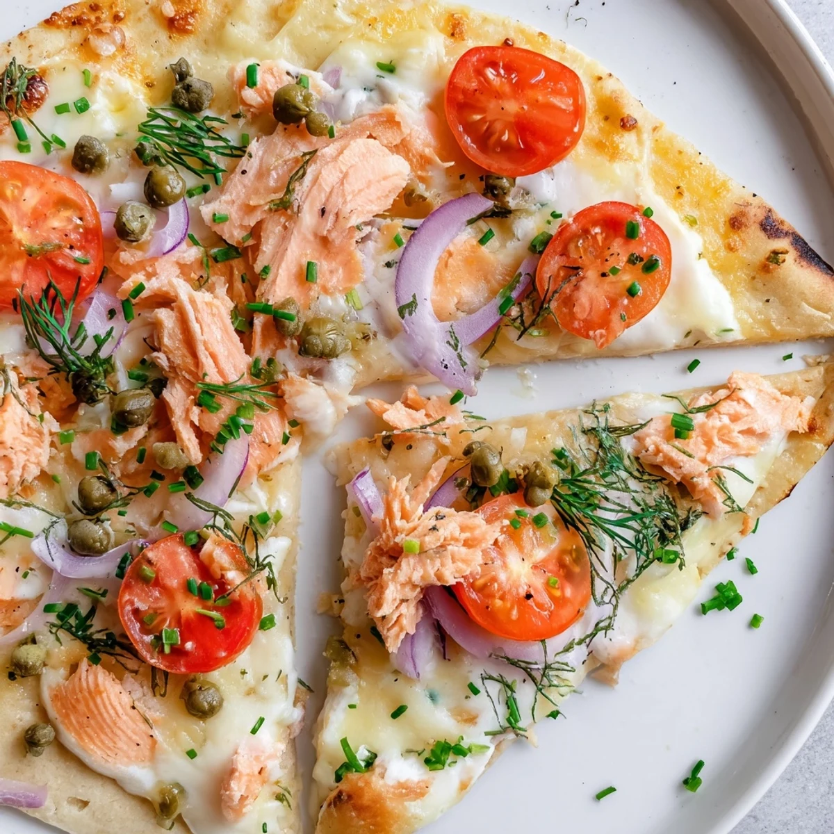 Golden baked salmon tortilla pizza topped with cherry tomatoes and red onion slices