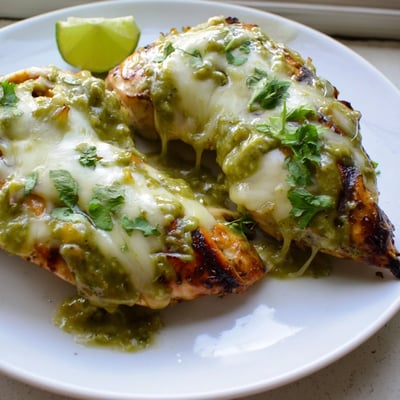 Sizzling salsa verde pepper jack chicken on a grill with gooey cheese and char marks