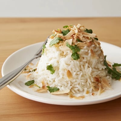 Fluffy coconut rice garnished with fresh cilantro beside a curry dish
